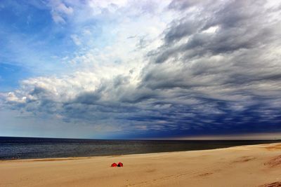 Scenic view of beach against cloudy sky