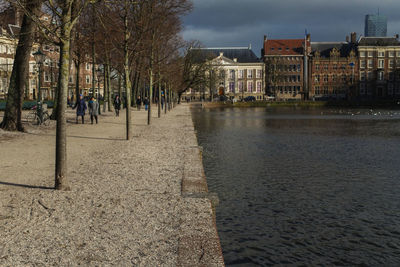 Buildings by river against sky in city