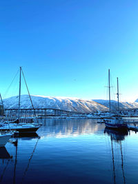 Boats in sea against clear blue sky