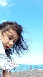 Girl standing at beach against blue sky