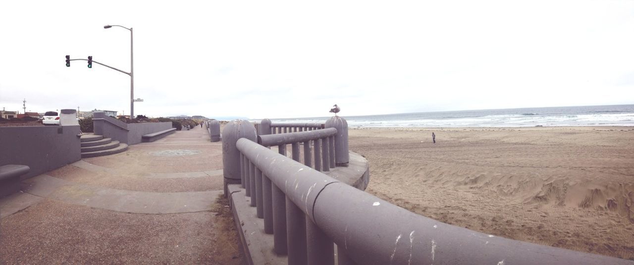 sea, clear sky, horizon over water, copy space, beach, water, sand, built structure, sky, transportation, shore, day, street light, outdoors, architecture, incidental people, road, nature, tranquility, tranquil scene