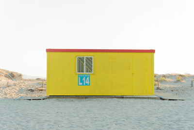 Yellow flag on building by sea against clear sky