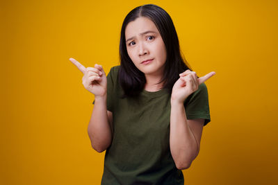 Portrait of beautiful woman standing against yellow background