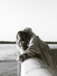 Side view of woman sitting against clear sky