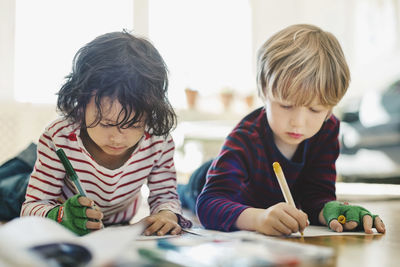 Friends lying on floor while coloring in books at home