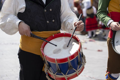 Midsection of men playing drums on street
