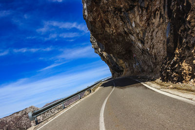 Road by trees against blue sky