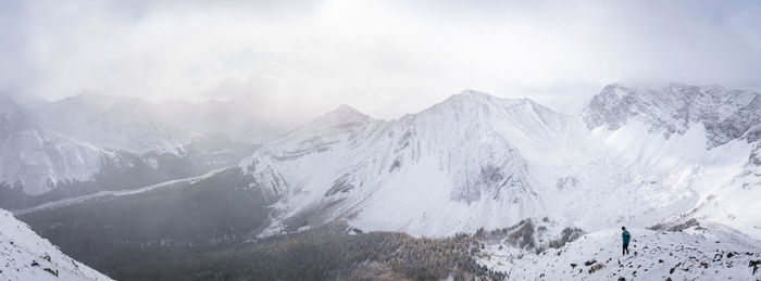 Hiker descending from the mountain into the valley during winter, panorama, kananaskis, canada