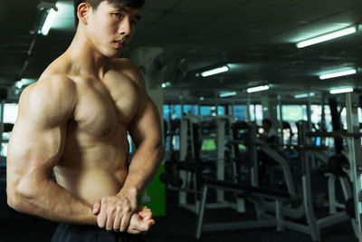 Shirtless man flexing muscle at gym