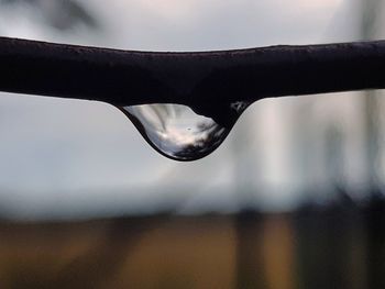 Close-up of wet glass against sky