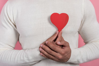 Midsection of woman holding heart shape with hands