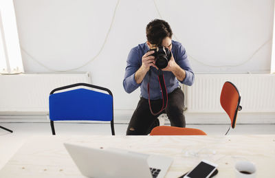 Male blogger photographing desk in creative office