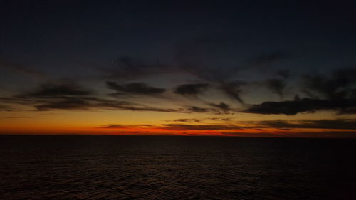 Scenic view of sea against dramatic sky during sunset