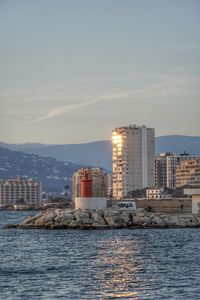 Sea by buildings against sky in city