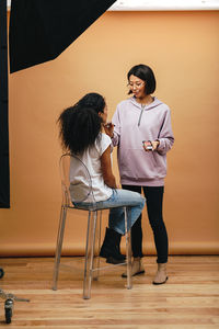 Full length of artist applying make-up on woman face in studio