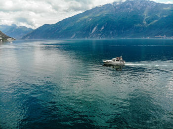 Sailboat sailing on sea against mountains