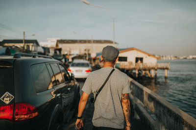 Rear view of man standing on car against sky