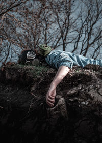 Low angle portrait of woman wearing gas mask while lying on land