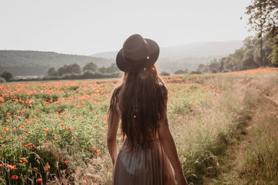 Rear view of woman standing on field against sky