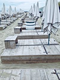Empty deck chairs on beach against sky