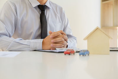 Low angle view of businessman with model home and toy cars