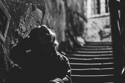 Rear view of woman sitting on street in city