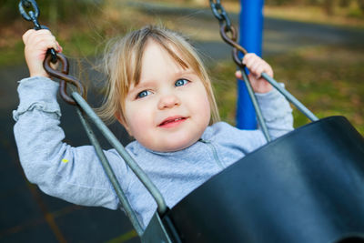 Portrait of a smiling girl on swing in playground