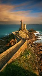 Lighthouse by sea against sky