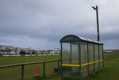 Built structure on field by buildings against sky