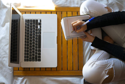 Top view of a woman working in bed and writing on her datebook.