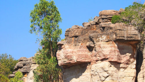 Low angle view of cliff against clear blue sky