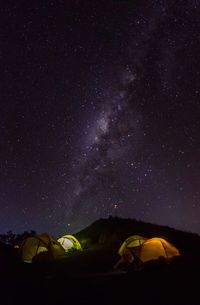 Illuminated tents on field against sky at night