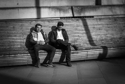 Full length of man sitting on wall
