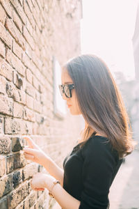 Side view of young woman standing by wall