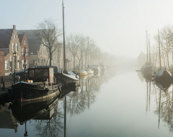 Boats moored in canal against sky