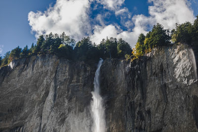 Low angle view of waterfall in forest against sky