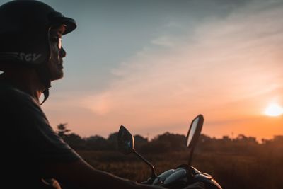Portrait of man riding motorcycle against sky during sunset