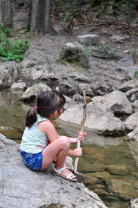 Side view of girl sitting on rock