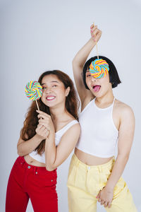 Lesbian couple holding lollipop against white background