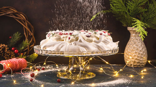 View of cake with plant and christmas lighting on table