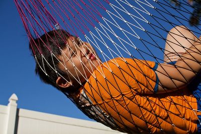 Boy lying in hammock hanging outdoors