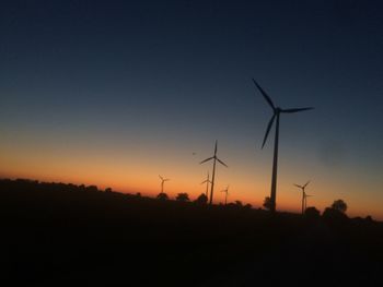 Silhouette windmill on field against clear sky during sunset