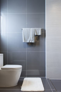 White flush toilet bowl and clean towels on rack in bathroom.