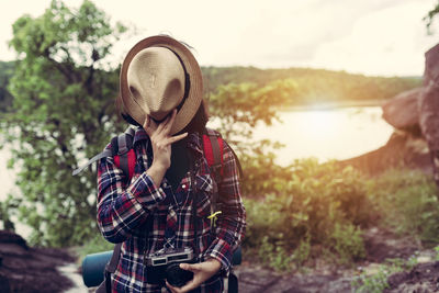 Hiker covering face with hat on mountain