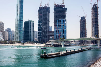 Boats in river by buildings against sky in city