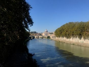 Scenic view of river by buildings against clear blue sky