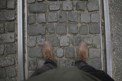 Low section of man standing on cobblestone