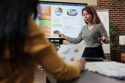 Woman explaining chart and graphs to colleagues at office