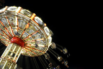 Low angle view of illuminated lighting equipment against black background