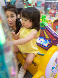 Smiling cute baby girl and mother at amusement arcade